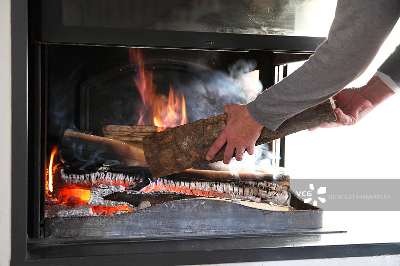 手将木头放入壁炉图片素材