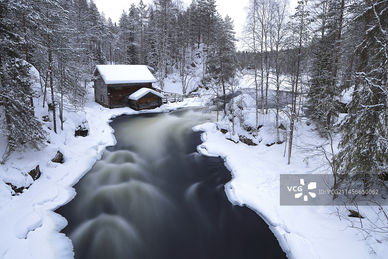 冬季日出时分，芬兰奥兰卡公园河边的木屋图片素材