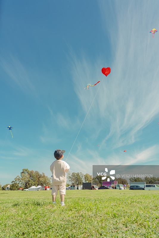 草坪上放红风筝的小男孩图片素材