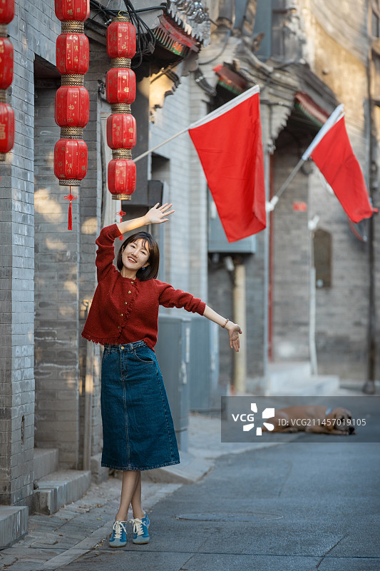 北京国庆节胡同里快乐的年轻女子和她的狗玩耍图片素材