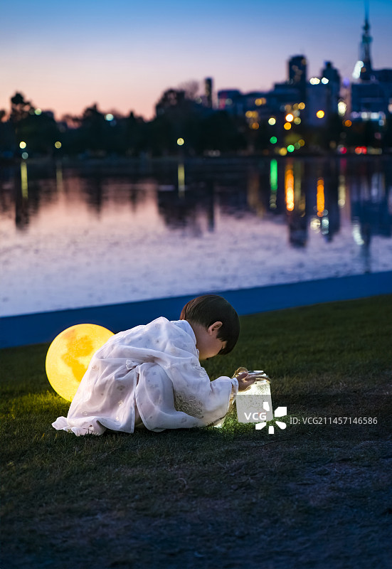 城市湖畔中秋之夜的汉服男孩与月亮灯图片素材