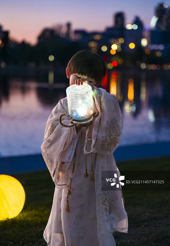 城市湖畔中秋之夜汉服男孩手捧灯光瓶图片素材