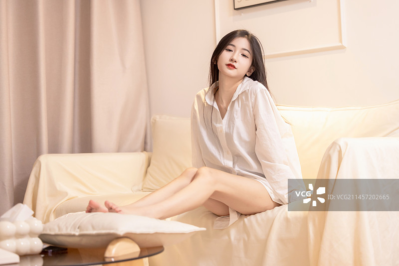 一名穿着白色长衬衫的美女坐在沙发上图片素材