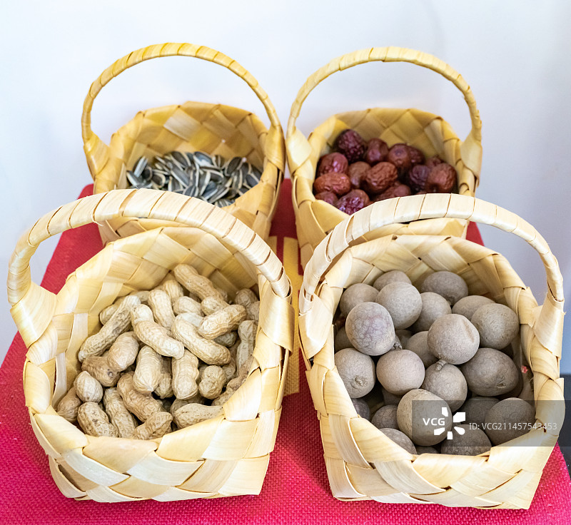 中国美术工艺拍摄主题，四个黄色竹子编织物鱼篓里的早生贵子桂圆瓜子红枣和花生，户外白昼无人图像摄影图片素材