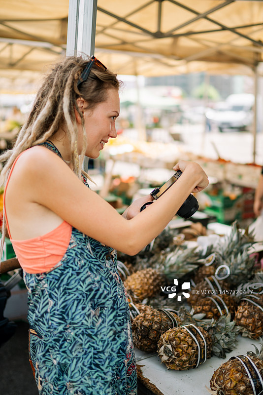 在市场上拍摄新鲜蔬菜的快乐年轻女人图片素材