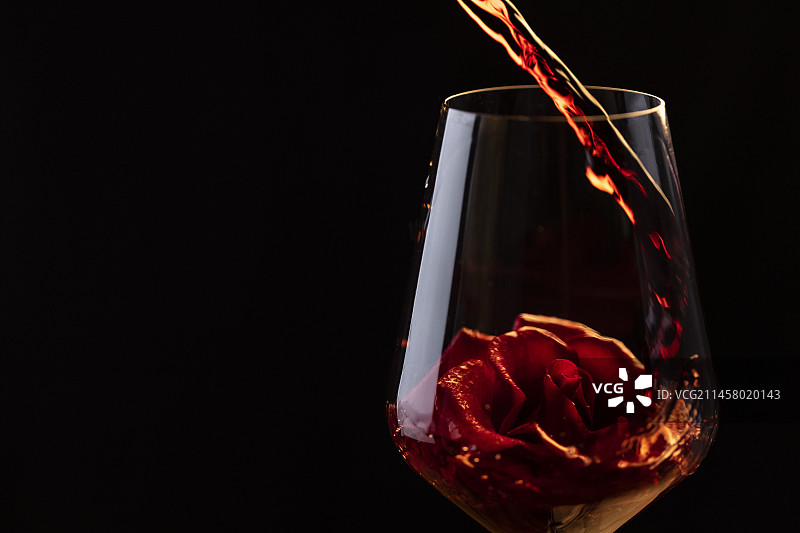 红酒倒入有玫瑰花的玻璃杯中图片素材