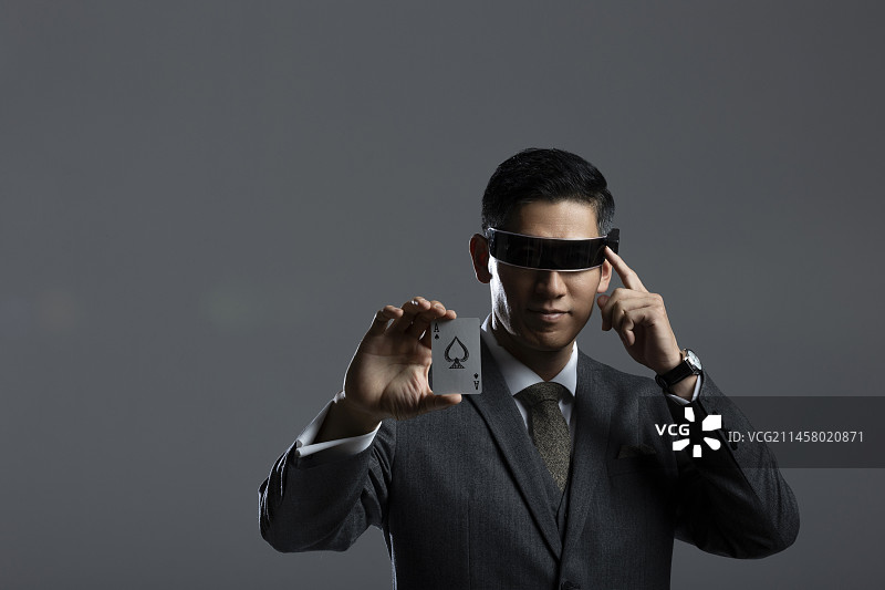 成熟商务男士戴着科技眼镜，拿着纸牌黑桃A肖像图片素材