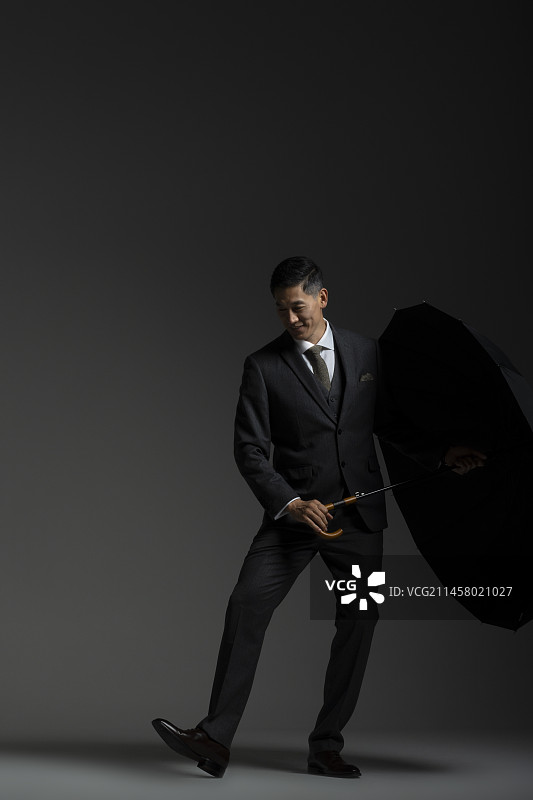 成熟商务男士拿着雨伞跳舞嬉戏图片素材