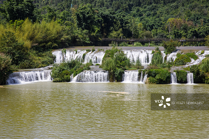 中国云南曲靖市罗平县九龙瀑布群景区，迎宾瀑布，迎宾桥，草坪，风车图片素材