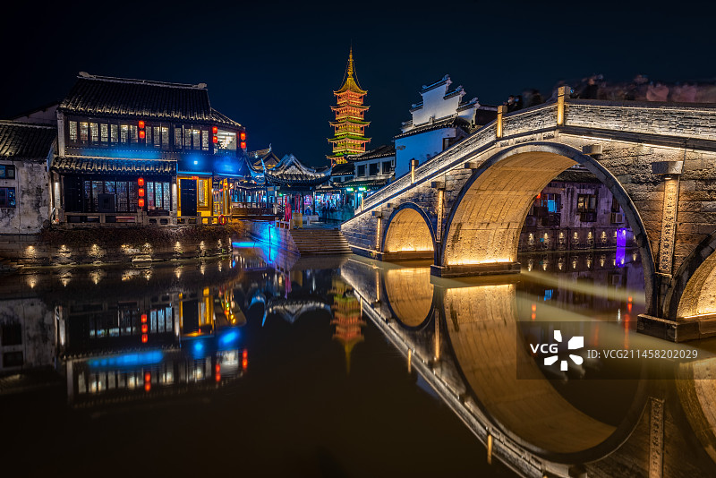 太阳下山后天空仍然保留一点深蓝色，夜色中的苏州昆山千灯古镇夜景灯生动描绘出古镇的轮廓，水面形成倒影图片素材
