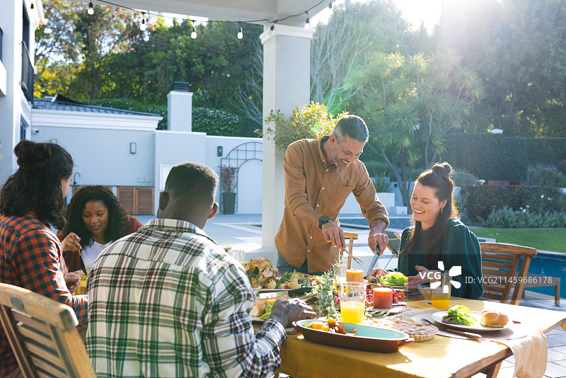 朋友们在阳光明媚的花园里共进感恩节晚餐图片素材