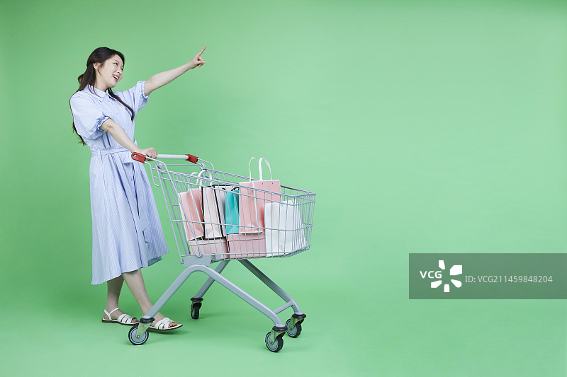 手推购物车和购物袋礼品盒的绿色消费者女人图片素材