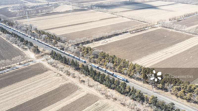 下行货车行驶在早春的京哈线扶余段色块交错的田野旁图片素材