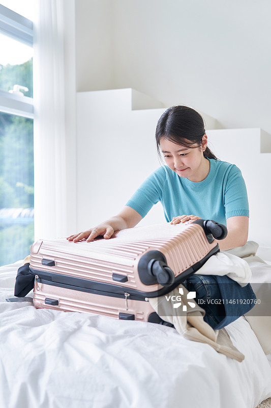 20多岁的年轻女子拖着行李箱旅行图片素材