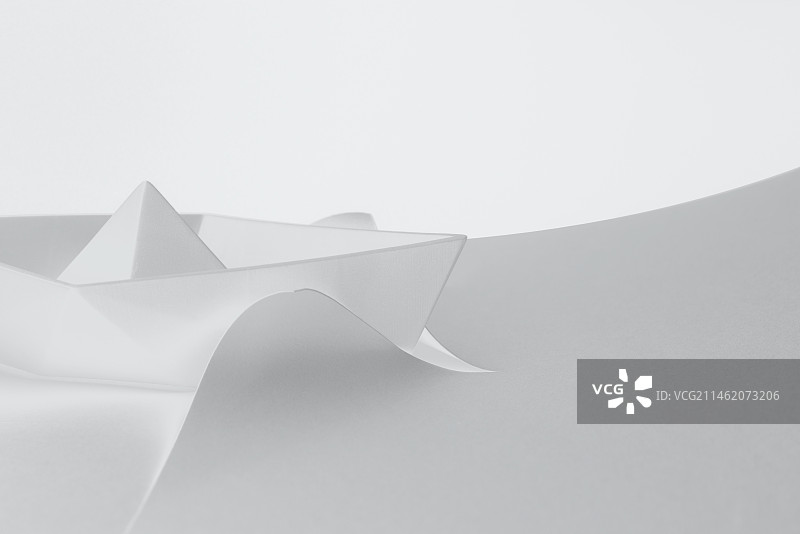 白色背景下在白纸上破浪前行的船微缩创意图图片素材