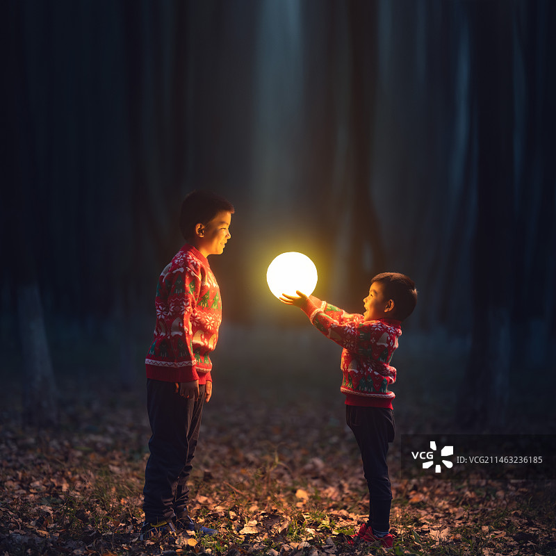 森林里穿着圣诞毛衣的两个男孩拿着月亮图片素材
