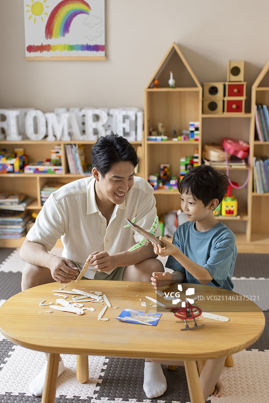Young Chinese father an son making wooden plane图片素材
