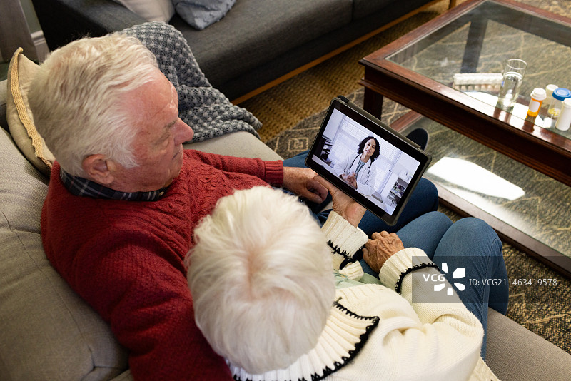 在阳光明媚的客厅里与医生进行视频通话的年长的白人夫妇图片素材