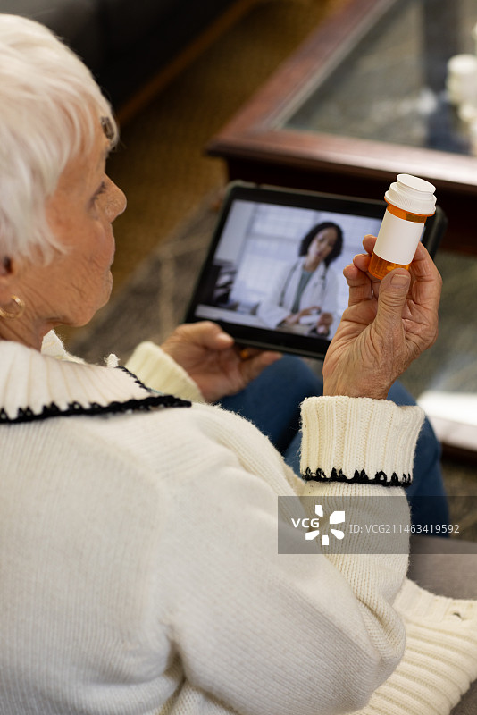 年长的白人妇女在阳光明媚的客厅里与医生进行视频通话图片素材