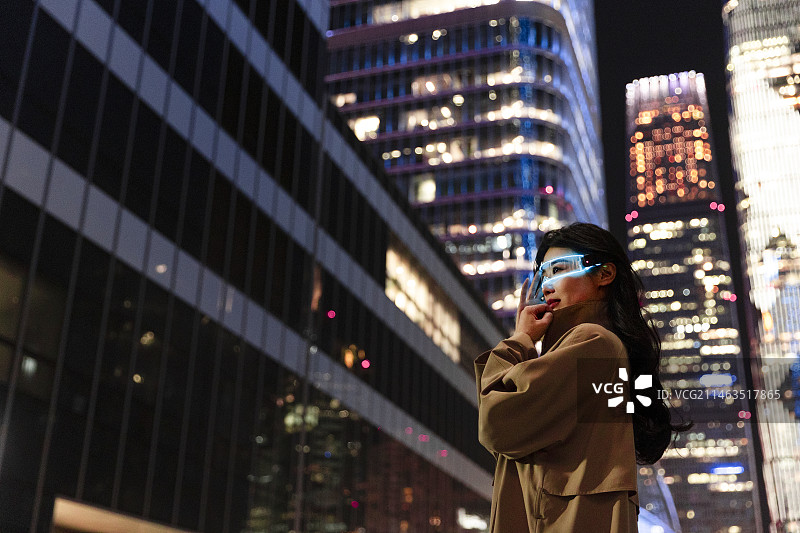夜晚未来高知商务女子戴着智能眼镜在城市街道上图片素材