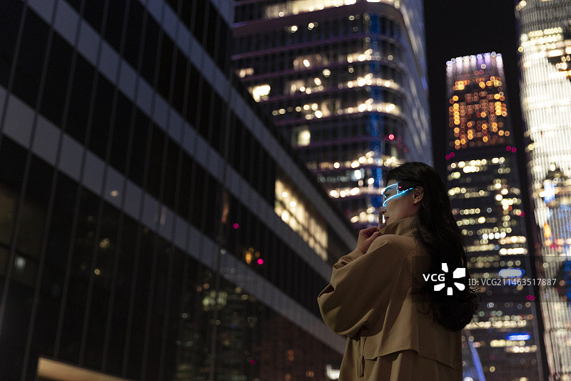 夜晚未来女子戴着智能眼镜在城市街道上图片素材