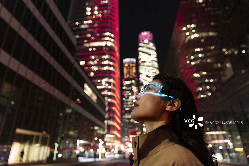 未来高知女子戴着智能眼镜看城市夜景，感知未知世界图片素材
