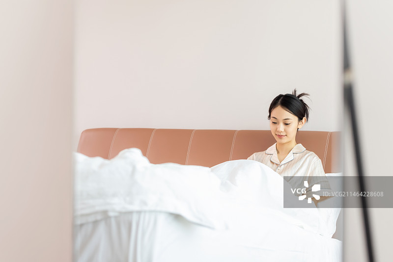 年轻的女孩在床上玩手机图片素材