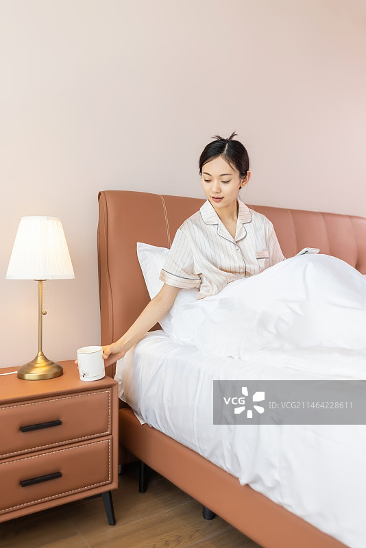 年轻的女孩在床上玩手机图片素材