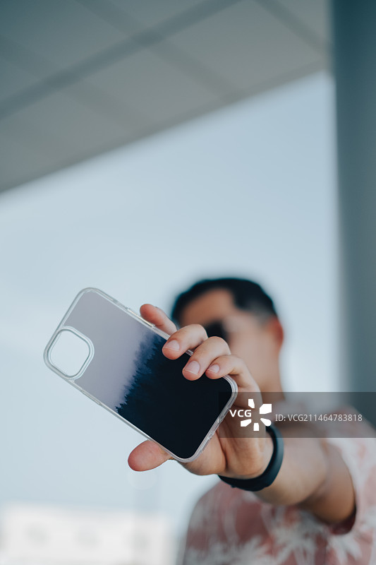 手持空手机壳的英俊年轻男子肖像，美国德克萨斯州科珀斯克里斯蒂图片素材