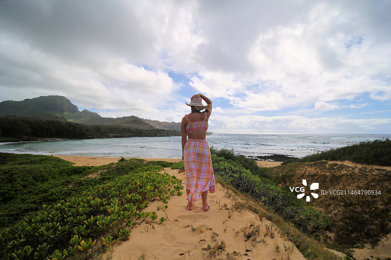 女子身穿太阳裙走在沙滩上，身后是可爱岛，夏威夷，美国图片素材