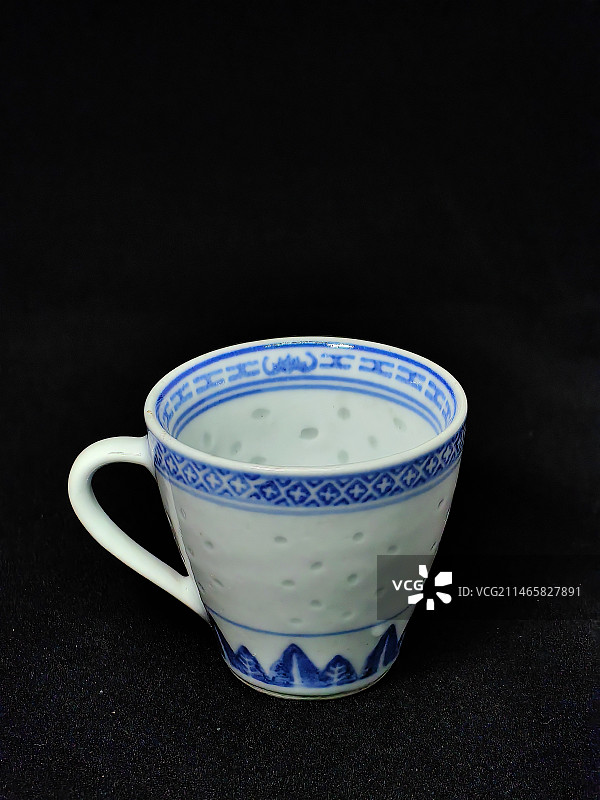 黑色背景下的空杯子特写镜头，景德镇青花玲珑瓷杯图片素材