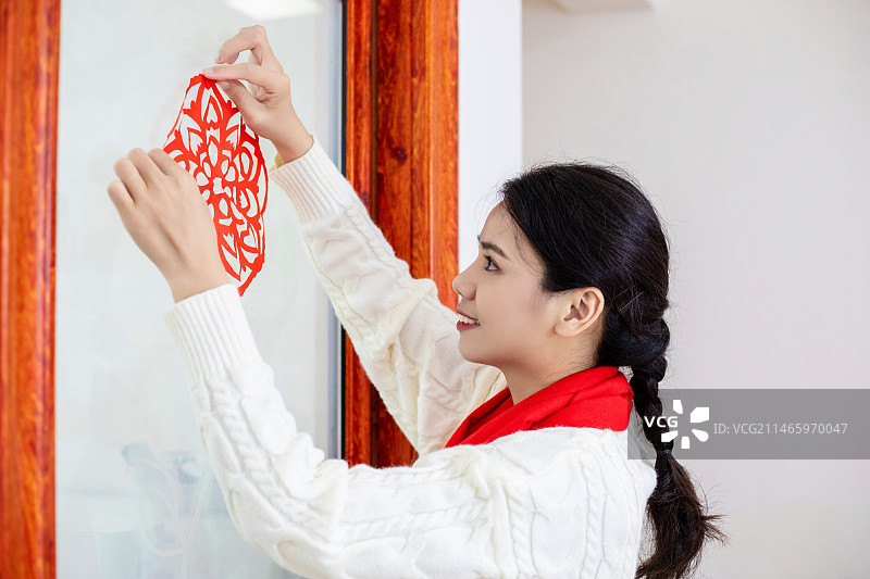 春节主题一个中国女性在家里贴窗花图片素材