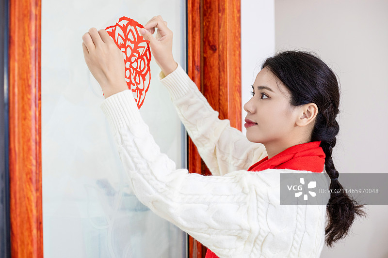 春节主题一个中国女性在家里贴窗花图片素材