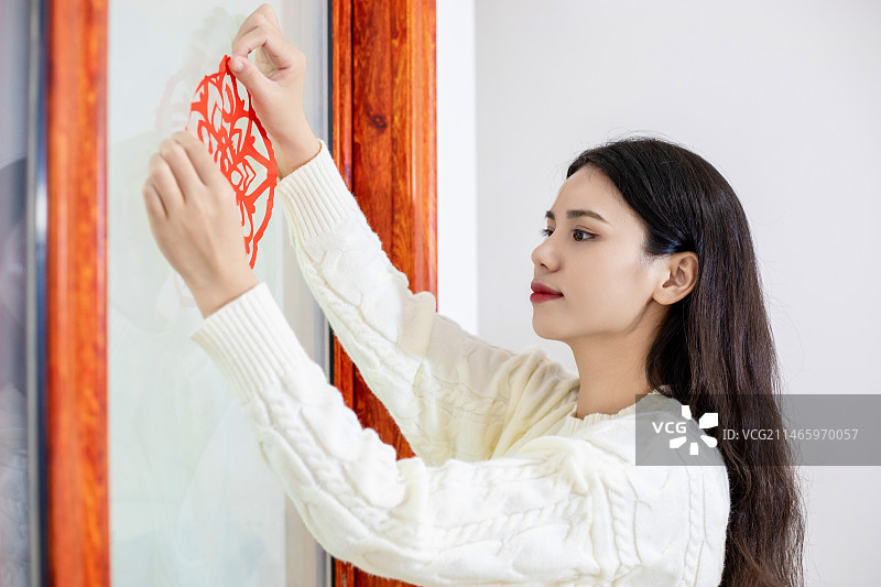春节主题一个中国女性在家里贴窗花图片素材