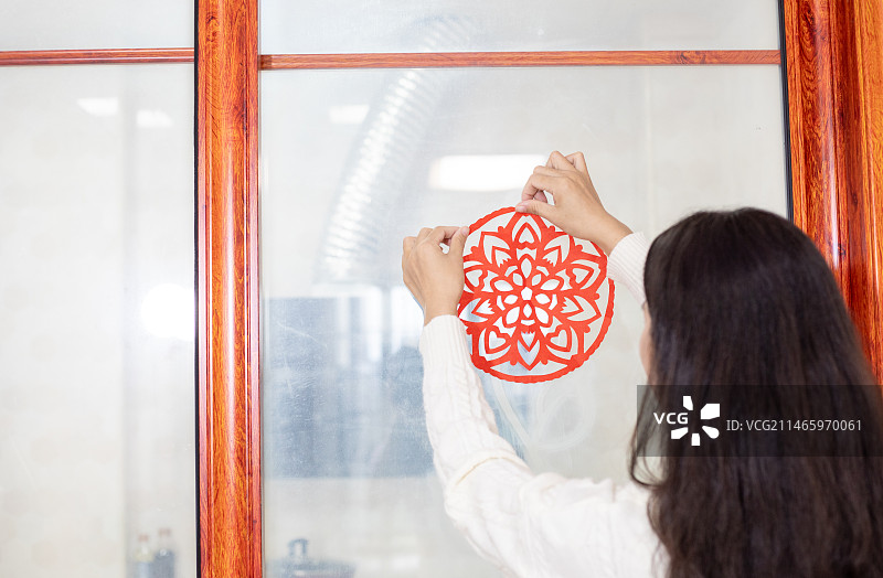 春节主题一个中国女性在家里贴窗花图片素材