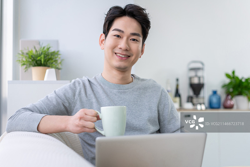 年轻男子在沙发上使用笔记本电脑图片素材
