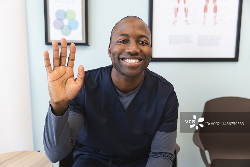 快乐的非洲裔男医生在医院候诊室进行视频通话图片素材