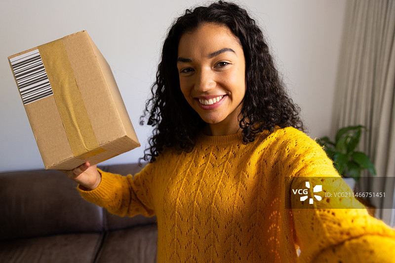 快乐的双种族女人在家里拿着包裹图片素材