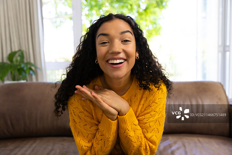 穿黄色毛衣的混血女子在家进行视频通话图片素材