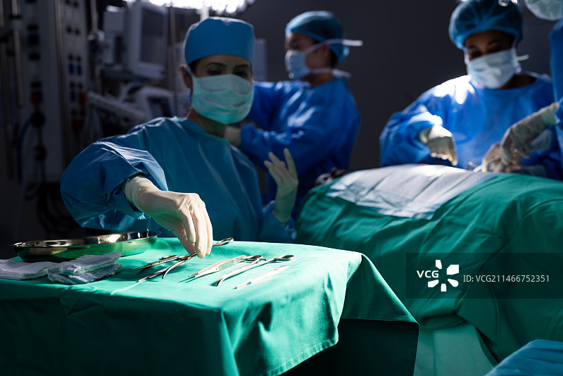 戴着口罩在医院手术室做手术的女性医生们图片素材