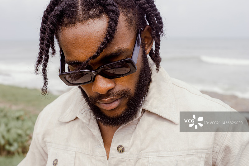 戴墨镜的年轻男人站在阿克拉海滩图片素材