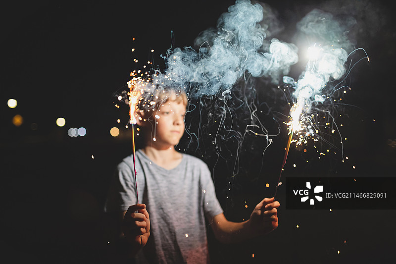 男孩在夜晚户外手持烟花，美国密苏里州圣查尔斯图片素材