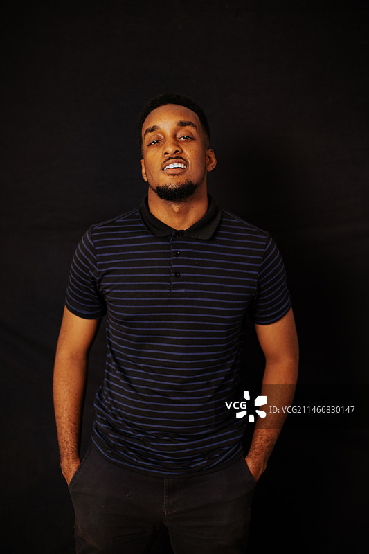 黑色背景下站立的微笑男人肖像，阿克拉，加纳图片素材