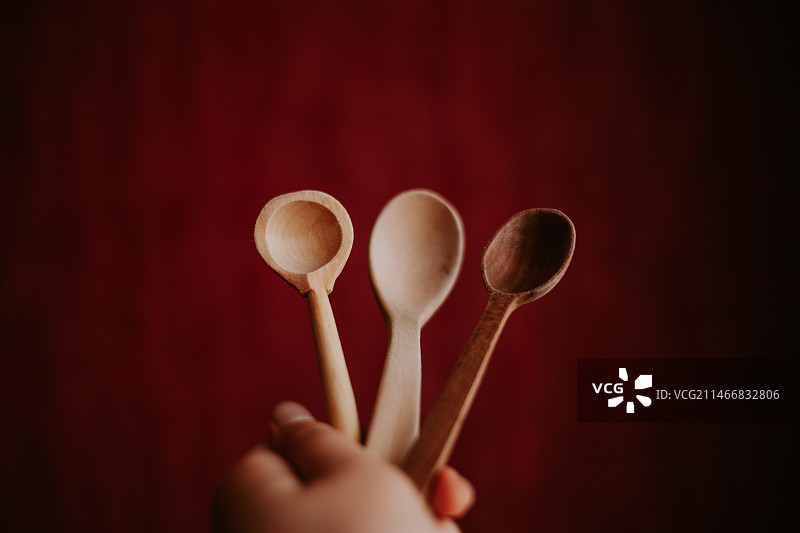 裁剪的手拿着勺子在红色背景前，白俄罗斯图片素材