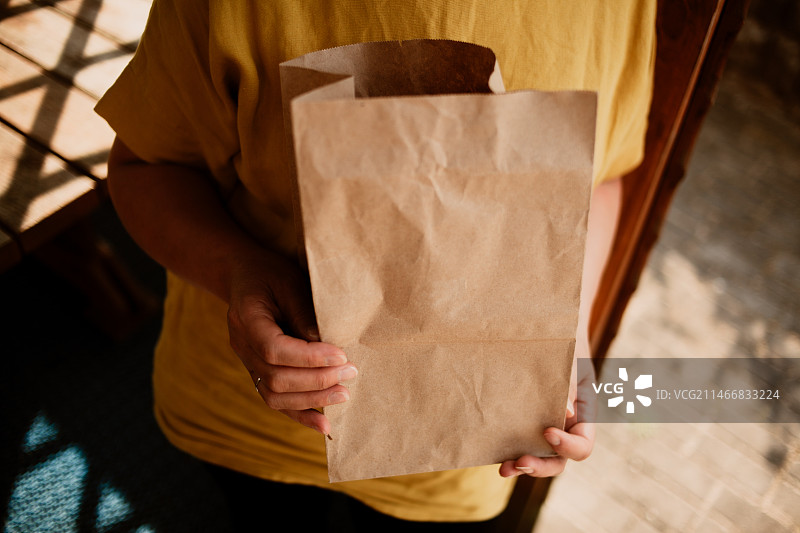 白俄罗斯，男子站在走廊上手提纸袋的身体中部特写图片素材
