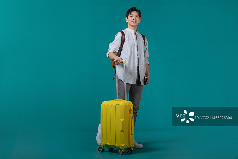 棚拍拿着行李箱的年轻男子图片素材
