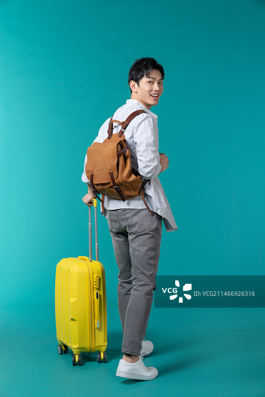 棚拍拿着行李箱的年轻男子图片素材