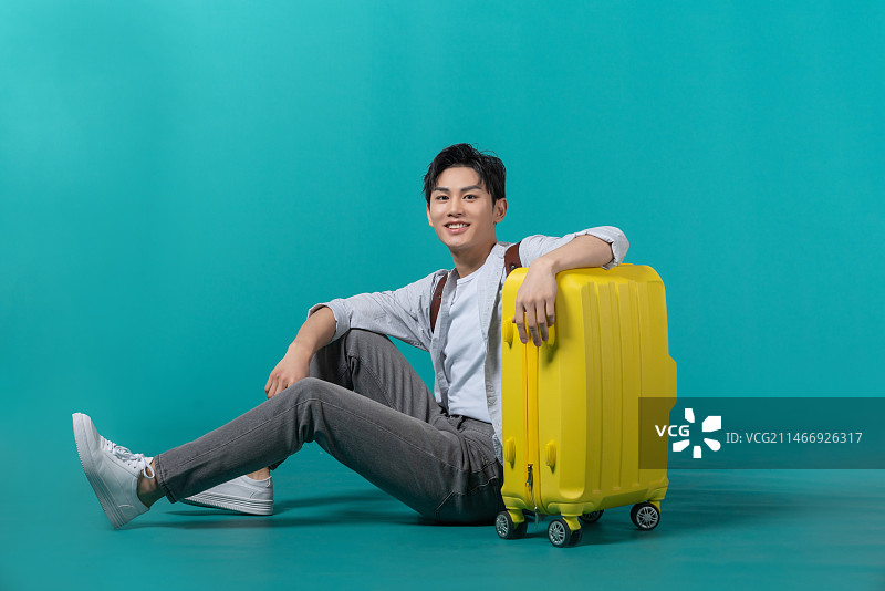棚拍拿着行李箱的年轻男子图片素材
