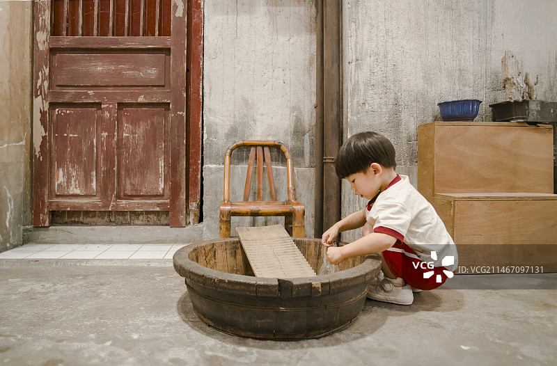 老房子木脚盆处的小男孩图片素材