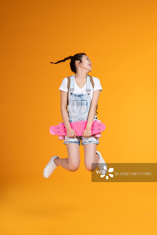 棚拍拿着滑板的年轻女子图片素材